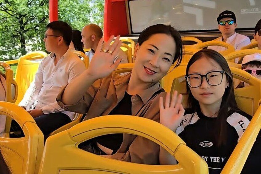A group of people on a yellow bus, some with their hands raised. 2