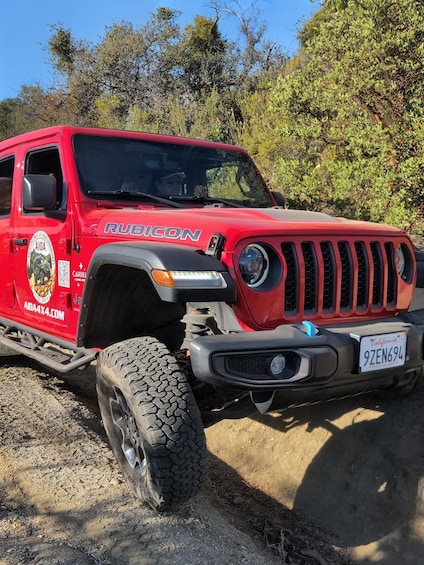 A red Rubicon SUV parked on a dirt road with a license plate 9ZEN694. 2