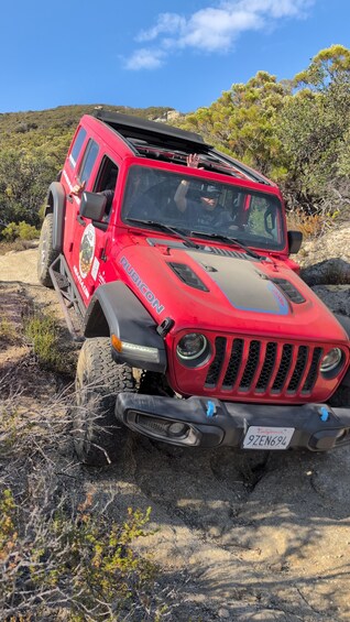 A red off-road vehicle with a California license plate in a rugged outdoor setting. 3