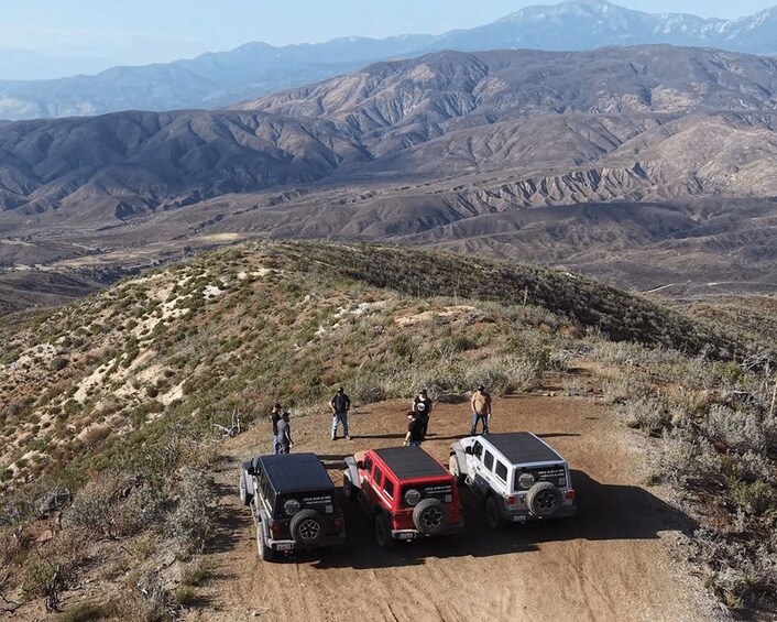 A group of off-road vehicles on a dirt path with a mountainous landscape in the background. 1
