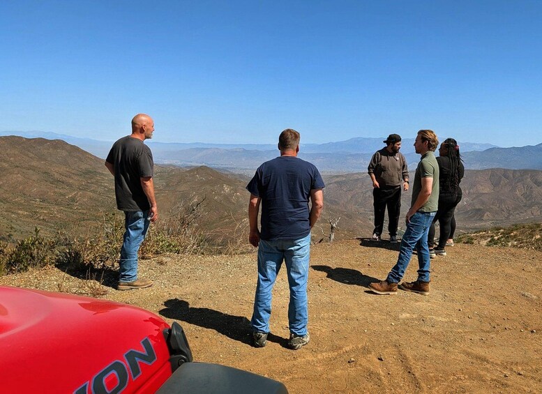 A group of people standing on a hilltop overlooking a mountainous landscape. 4