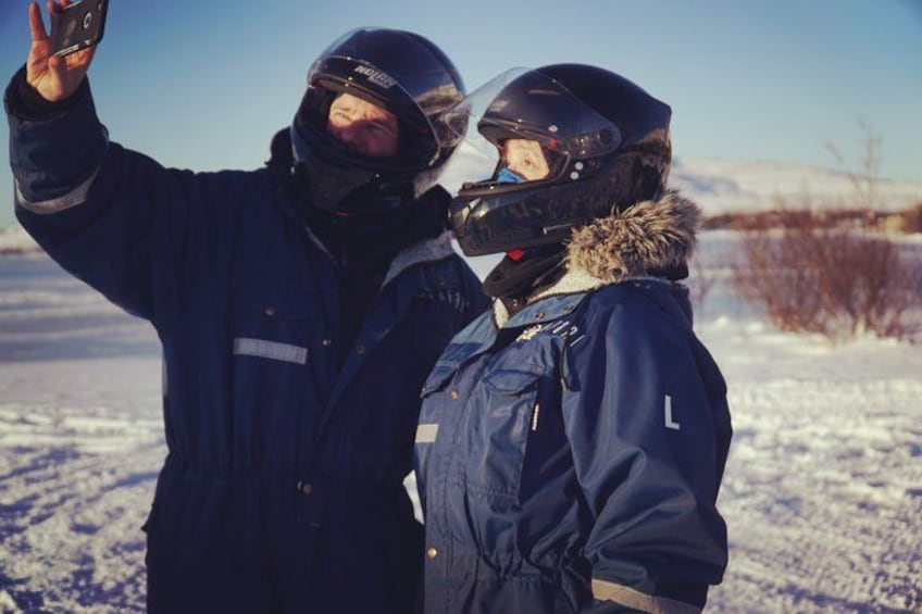 Two people in winter jackets and helmets taking a selfie in a snowy field. 5