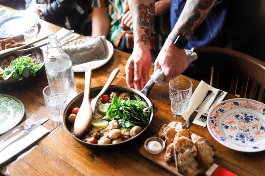 A wooden table with a meal, including a bowl of salad, bread, and a bottle of water. 3