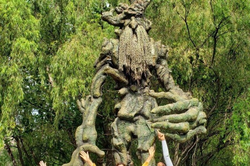 A large tree sculpture with intricate branches and roots, surrounded by lush green foliage. 5