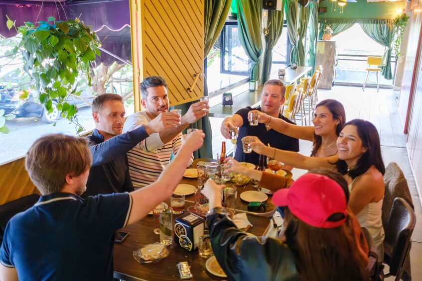 Un grupo de personas brindando con bebidas en una mesa con varias botellas y vasos. 1