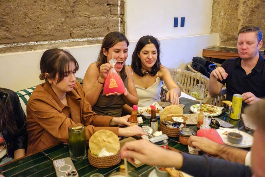 Un grupo de personas cenando en un restaurante con una pared de ladrillo rústica de fondo. 5