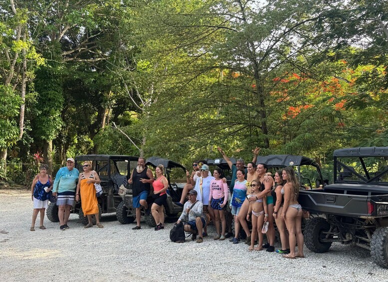 Un grupo de personas reunidas cerca de vehículos todoterreno en un entorno natural con árboles y follaje. 4