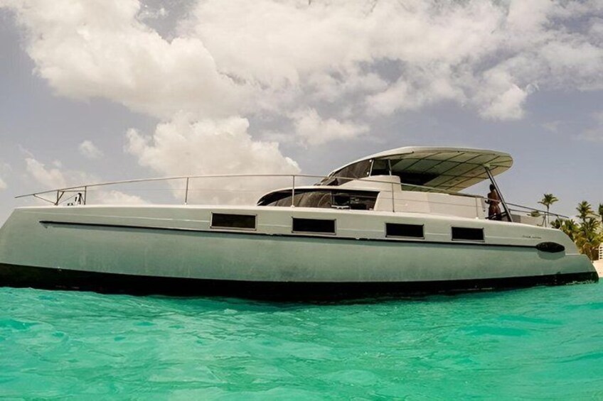 A large, modern yacht with a covered deck, floating on turquoise water. 5
