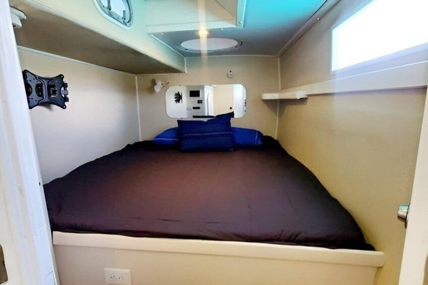A compact interior with a bed, a white ceiling with a circular light fixture, and a small window. 3