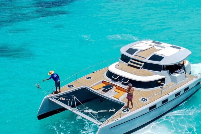 A yacht on turquoise water with a person standing on the deck. 2