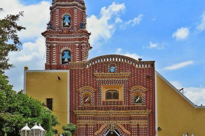 A church with a red and yellow facade, a bell tower, and a clock. 2