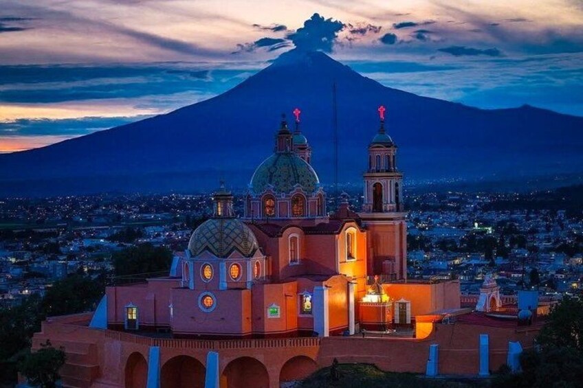 A church with a dome and two towers, set against a backdrop of a mountain and a cityscape at dusk. 1