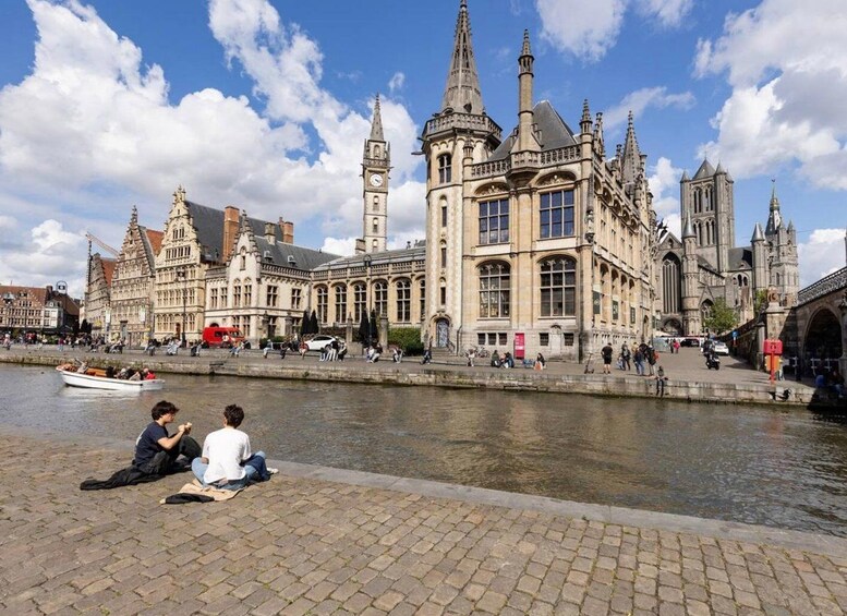 Ein historisches Gebäude mit aufwendiger Architektur, ein Fluss mit Booten und Menschen, die am Wasser sitzen. 3