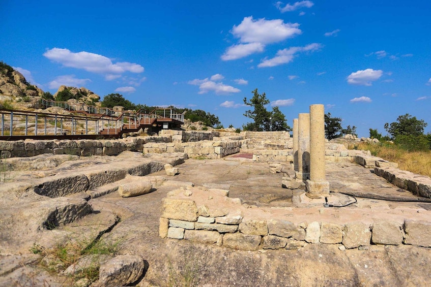 Ancient ruins with stone structures and a metal walkway. 3