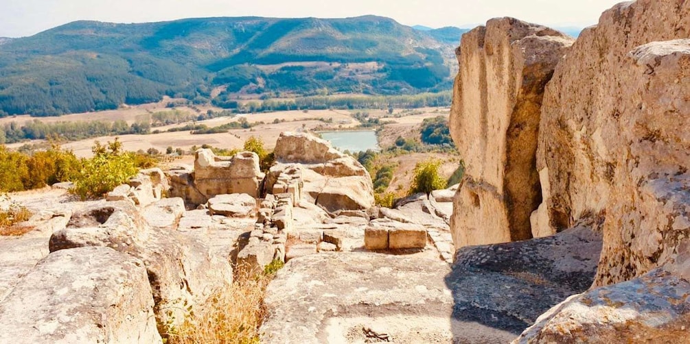 A rocky landscape with ruins and a lake in the background. 2