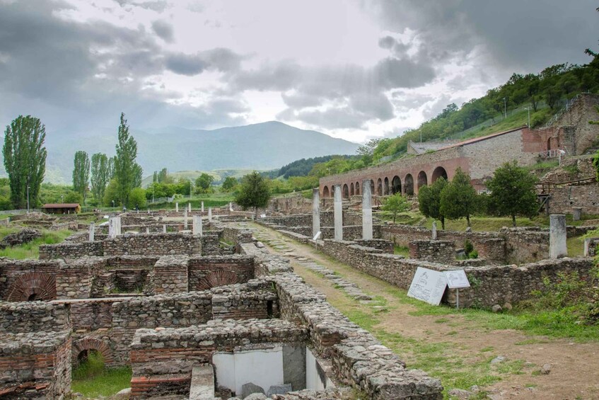 Ancient ruins with stone walls and arches, a pathway, and a mountain in the background. 4
