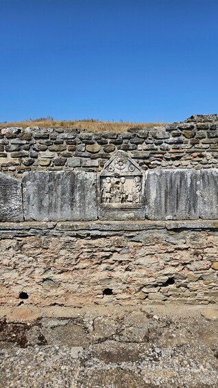 Ancient ruins with stone walls and a central carved stone. 2