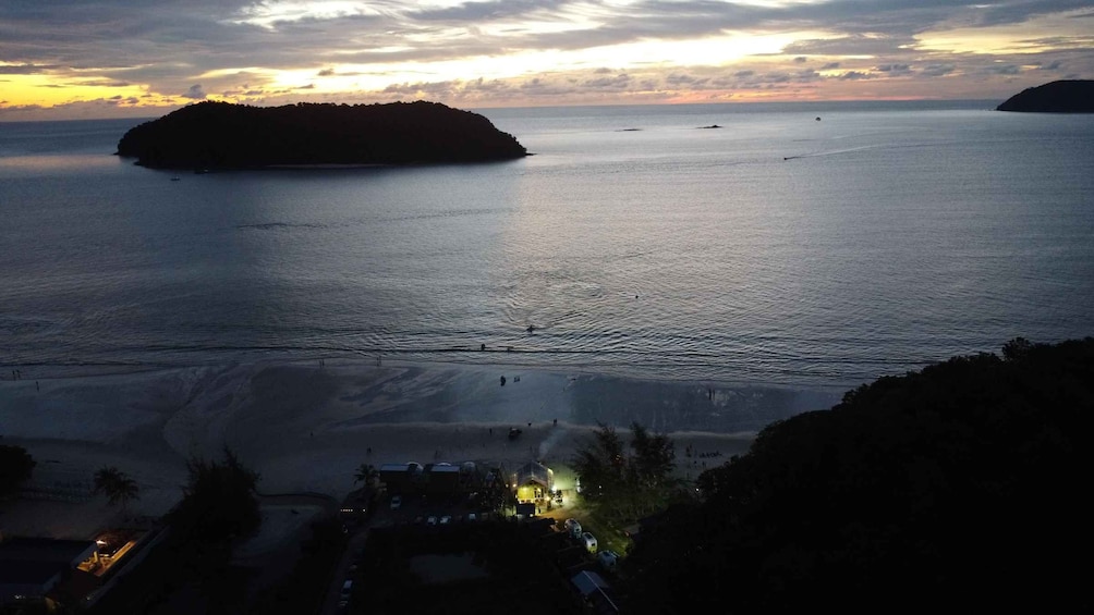 A coastal scene with a beach, a small island, and a sunset. 3