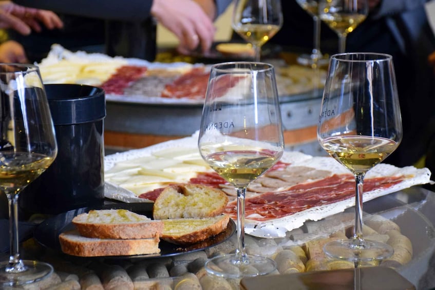 A charcuterie board with cheese, cured meats, and bread, accompanied by wine glasses. 1