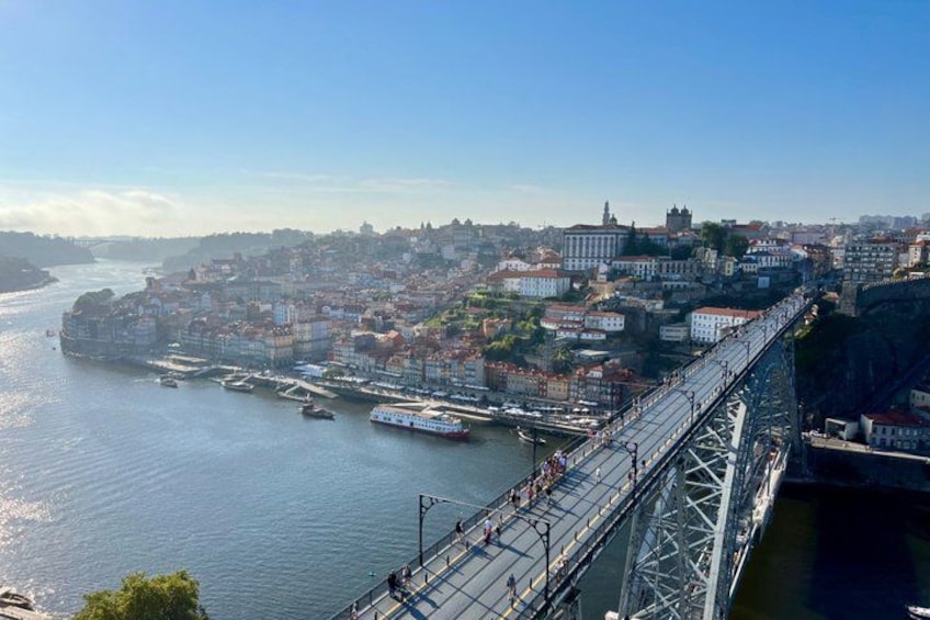 A river with a bridge, boats, and a cityscape with buildings and a hill. 1