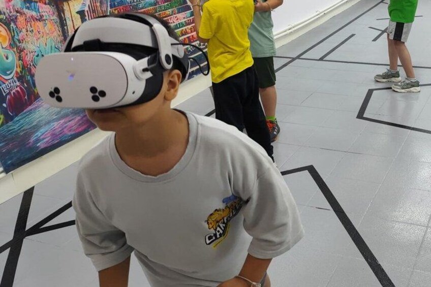 A person wearing a virtual reality headset in an indoor setting with a colorful mural in the background. 2
