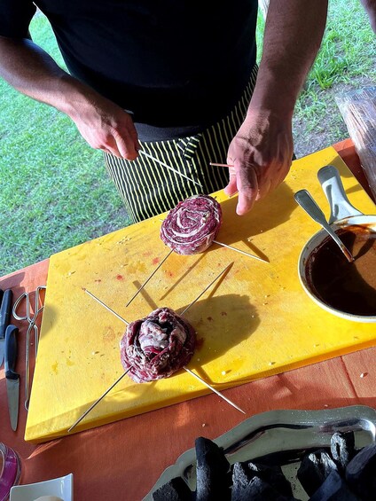 Henkilö grillaa lihaa ulkona keltaisella leikkuulaudalla. 5