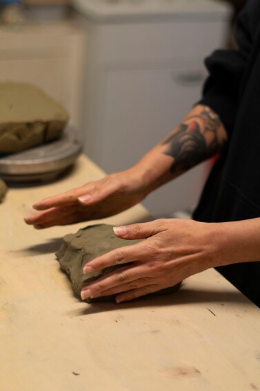 A person molding clay on a workbench. 1