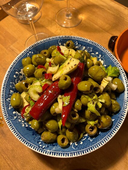 A plate of olives, red chili peppers, and garlic on a blue patterned plate. 2