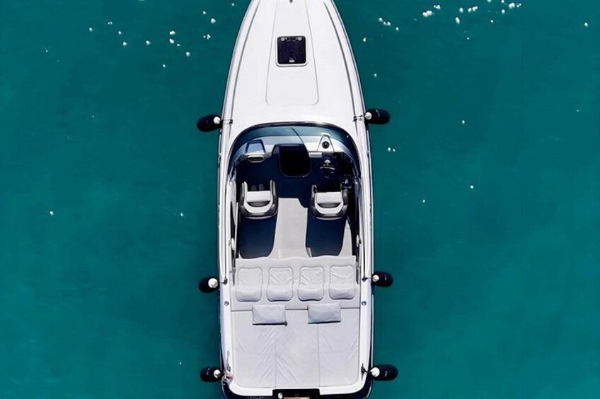 Un barco blanco con cabina y zona de estar en aguas turquesas. 1