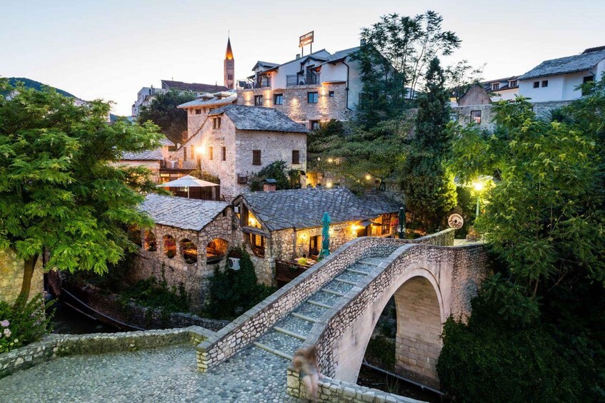 A historic town with stone buildings, a bridge, and lush greenery. 5