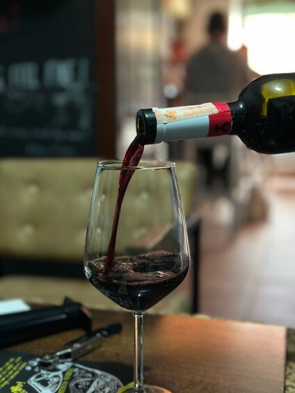 A bottle of red wine being poured into a glass. 2