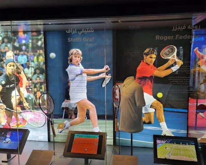 Tennismatkaottelu, jossa on esillä elämänkokoisia pelaajahahmoja toiminnassa, tulostaulu ja digitaalinen näyttö. 4