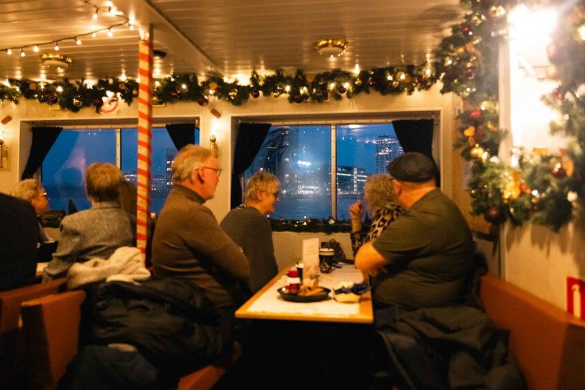 A restaurant with festive decorations, including garlands and a Christmas tree, and a view of the cityscape at night. 2