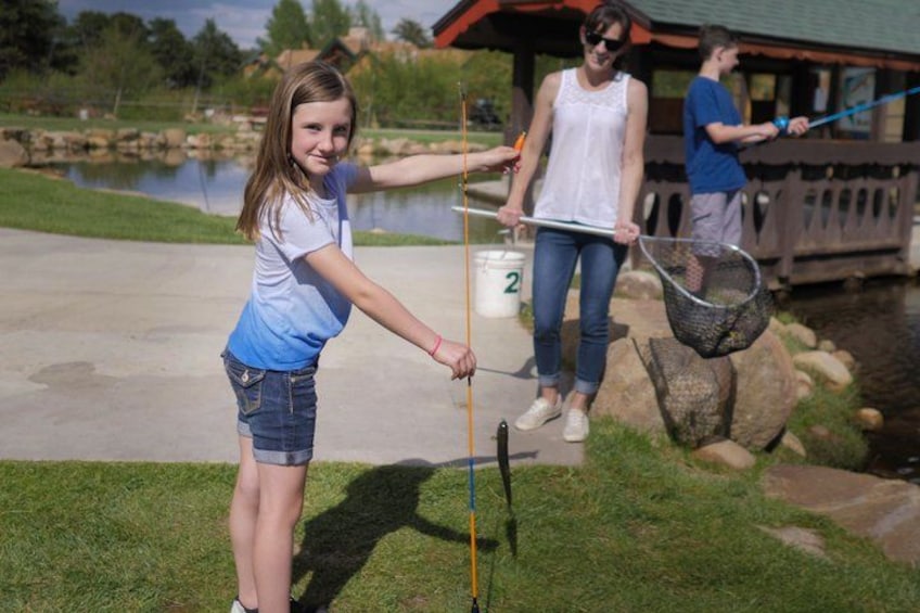 A child fishing by a pond with an adult assisting. 4