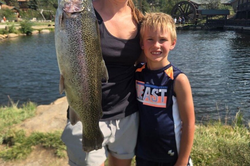 A person holding a fish, a water body, and a wooden structure. 3