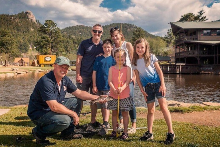 A family by a lake with a wooden lodge in the background. 5