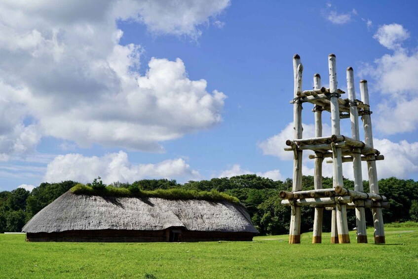 A thatched-roof hut and a wooden structure with vertical posts. 1