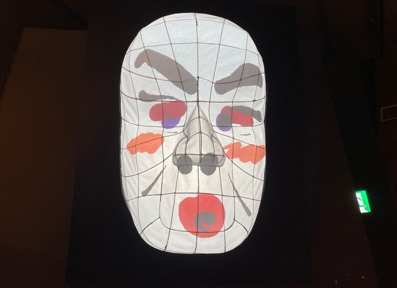 A large, illuminated face sculpture with grid lines and abstract shapes. 3