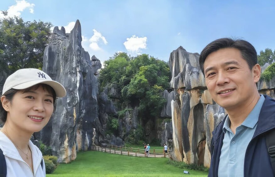 Two people standing in front of a rocky landscape with a fence and a grassy area. 1