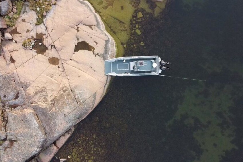 A boat anchored near a rocky shoreline with clear water. 4