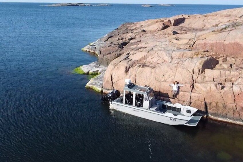 A boat docked at a rocky shore with a person standing on the edge. 1