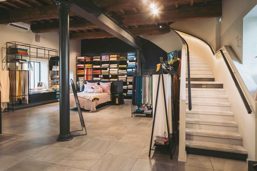 A modern interior with a staircase, shelves of textiles, and a bed. 3