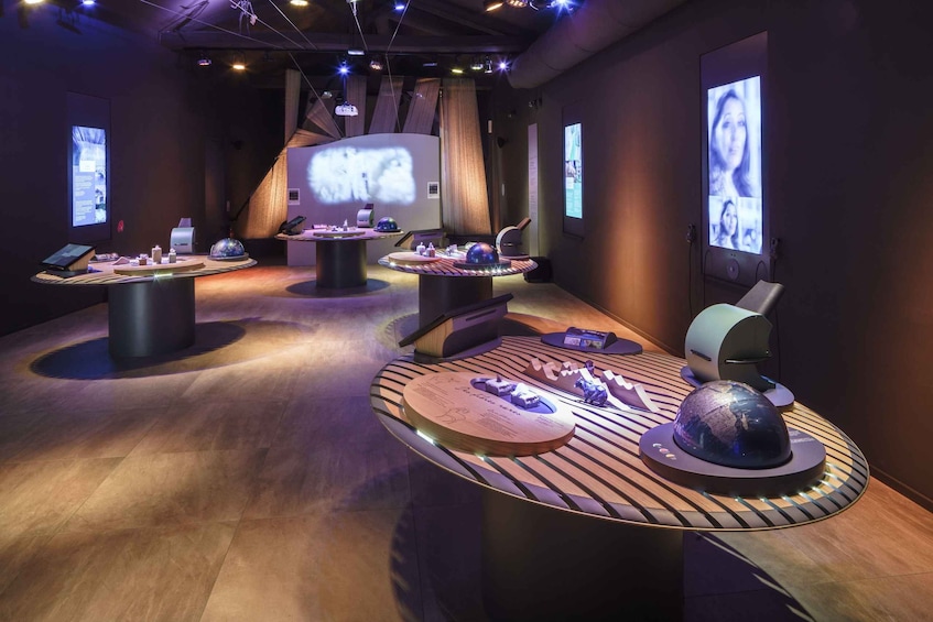 A modern exhibition space with interactive displays and projections on the walls. 5