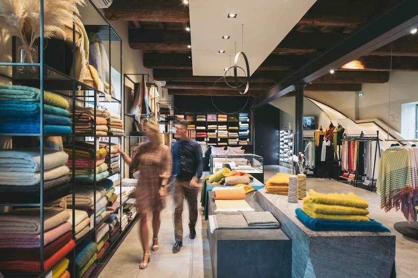A textile store with shelves of folded fabrics and a display of blankets. 4