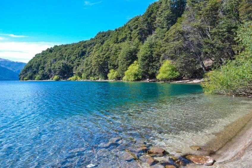 A clear lake with rocky shorelines and dense forested hills. 3