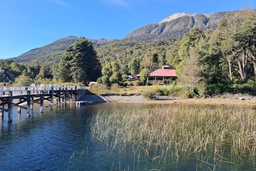 A wooden bridge over a river, a red-roofed building, and a mountain range in the background. 5