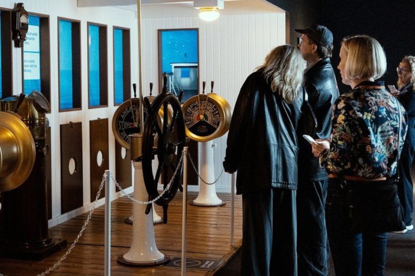 A room with maritime navigation instruments, including a ship's wheel and a brass telescope. 4