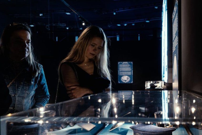 Two people observing an exhibit with glass cases and a display case with lights. 3