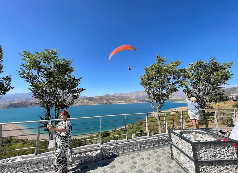 A person paragliding over a lake with mountains in the background. 1