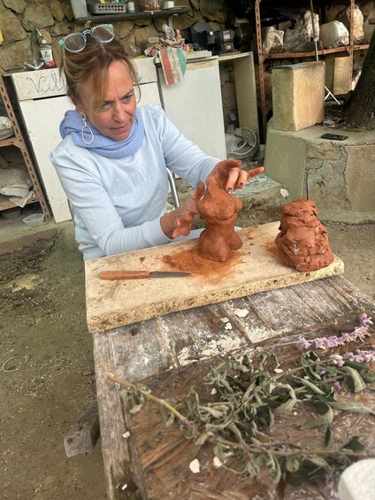 A person sculpting a clay figure outdoors. 5